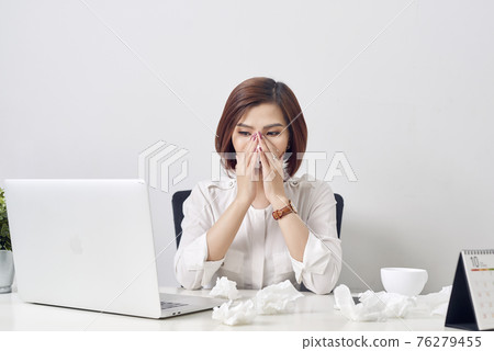 Sad exhausted woman with tissue suffering from cold while working with laptop at table 76279455