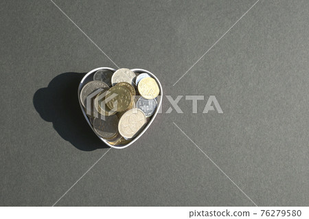 Coins in heart shaped container. Coins in heart shaped container. 76279580