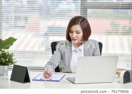 Young, attractive and confident business woman working in office Young, attractive and confident business woman working in office 76279666