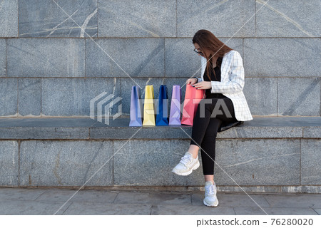 Young shopaholic woman with lots of shopping bags outdoors. Successful shopping 76280020