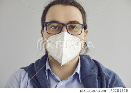 Headshot of man wearing KN95 face mask to protect himself from Covid 19 infection Headshot of man wearing KN95 face mask to protect himself from Covid 19 infection 76281256