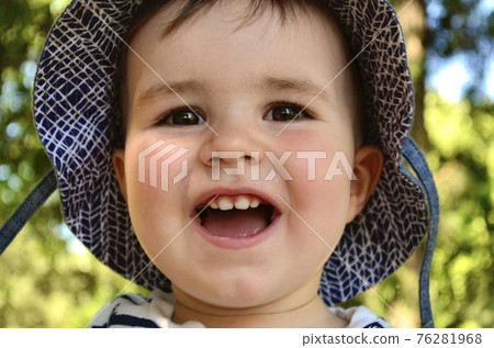 Portrait of a joyful baby with a smile in a summer hat with fields. 76281968