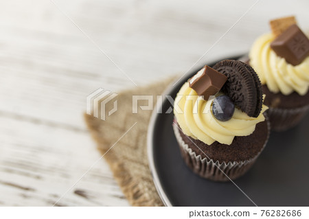 Muffins and cupcakes on plate, wooden background. Candies, cookie, cream cheese Muffins and cupcakes on plate, wooden background. Candies, cookie, cream cheese 76282686