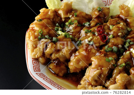 A black background shot of a deep-fried chicken with soy sauce and green onions on an octagonal plate A black background shot of a deep-fried chicken with soy sauce and green onions on an octagonal plate 76282814