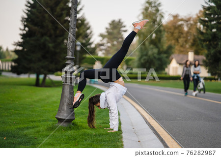 Attractive skinny woman doing a backbend while showing a somersault. Attractive skinny woman doing a backbend while showing a somersault. 76282987
