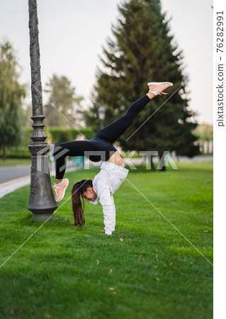Attractive skinny woman doing a backbend while showing a somersault. Attractive skinny woman doing a backbend while showing a somersault. 76282991