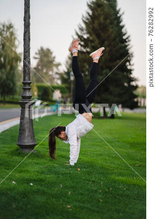 Attractive skinny woman doing a backbend while showing a somersault. Attractive skinny woman doing a backbend while showing a somersault. 76282992