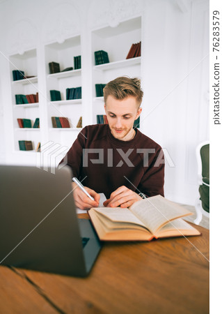 Young caucasian man college student studying with laptop distantly preparing for test exam writing essay doing homework at home or college library. Young caucasian man college student studying with laptop distantly preparing for test exam writing essay doing homework at home or college library. 76283579