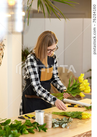 Florist woman makes a bouquet of tulips. Florist woman makes a bouquet of tulips. 76284160