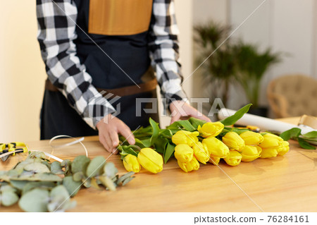 Florist woman makes a bouquet of fresh yellow tulips. Florist woman makes a bouquet of fresh yellow tulips. 76284161