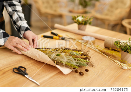 Florist woman makes bouquet of dried flowers 76284175