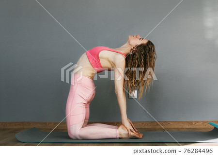 A young woman in sportswear practices yoga and performs asanas in a yoga class or at home. Yoga, sports, fitness. The concept of mental health and healthy lifestyle A young woman in sportswear practices yoga and performs asanas in a yoga class or at home. Yoga, sports, fitness. The concept of mental health and healthy lifestyle 76284496