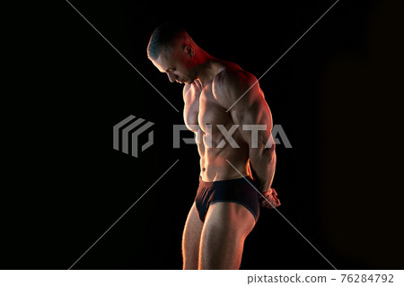 Active lifestyle concept. Professional bodybuilder showing perfect muscular body, lamps illumination on background Active lifestyle concept. Professional bodybuilder showing perfect muscular body, lamps illumination on background 76284792