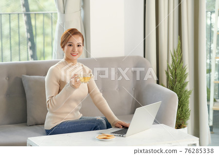 Surfing the net. Thoughtful young woman in eyewear using computer while sitting on the sofa at home Surfing the net. Thoughtful young woman in eyewear using computer while sitting on the sofa at home 76285338