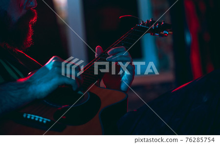 Close-up of musician performing in neon light. Concept of advertising, hobby, music, festival, entertainment. Close-up of musician performing in neon light. Concept of advertising, hobby, music, festival, entertainment. 76285754