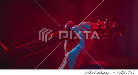 Close-up of musician performing in neon light. Concept of advertising, hobby, music, festival, entertainment. Close-up of musician performing in neon light. Concept of advertising, hobby, music, festival, entertainment. 76285755