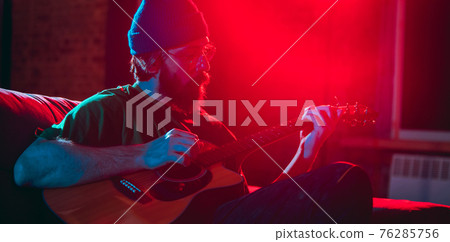 Close-up of musician performing in neon light. Concept of advertising, hobby, music, festival, entertainment. Close-up of musician performing in neon light. Concept of advertising, hobby, music, festival, entertainment. 76285756