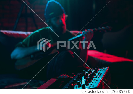 Close-up of musician performing in neon light. Concept of advertising, hobby, music, festival, entertainment. Close-up of musician performing in neon light. Concept of advertising, hobby, music, festival, entertainment. 76285758