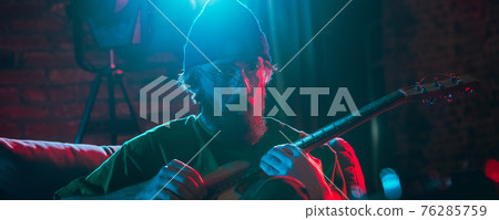 Close-up of musician performing in neon light. Concept of advertising, hobby, music, festival, entertainment. Close-up of musician performing in neon light. Concept of advertising, hobby, music, festival, entertainment. 76285759