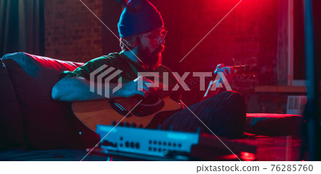 Close-up of musician performing in neon light. Concept of advertising, hobby, music, festival, entertainment. Close-up of musician performing in neon light. Concept of advertising, hobby, music, festival, entertainment. 76285760