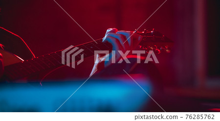 Close-up of musician performing in neon light. Concept of advertising, hobby, music, festival, entertainment. Close-up of musician performing in neon light. Concept of advertising, hobby, music, festival, entertainment. 76285762