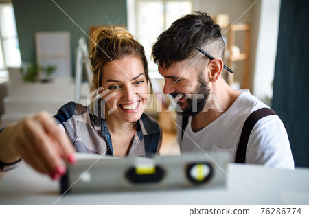 Mid adults couple with leveler indoors at home, relocation and diy concept. 76286774