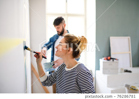 Mid adults couple painting wall indoors at home, relocation and diy concept. 76286781