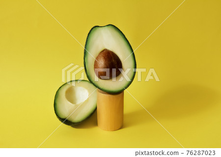 cut avocado fruit on celendric podium and yellow background 76287023