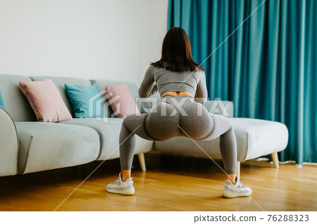 Young sporty woman doing squat morning exercise. home fitness routine Young sporty woman doing squat morning exercise. home fitness routine 76288323
