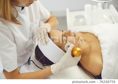 Cosmetologist making apparatus phonophoresis facail procedure for woman in beauty salon 76288759