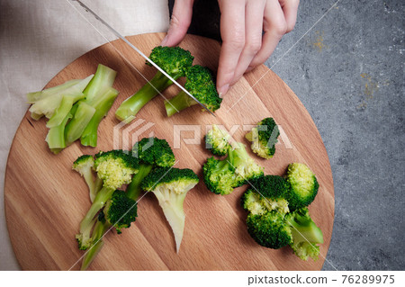 Chopping broccoli on a cutting board Chopping broccoli on a cutting board 76289975