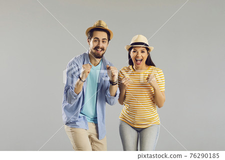 Portrait of cheerful couple in summer hat emotional rejoicing with raised fist 76290185