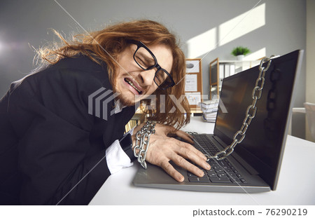 Side view of a tired crazy office worker who works overtime chained to a laptop and cries. 76290219