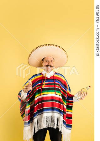 Portrait of happy man in bright garment, poncho isolated over yellow background Portrait of happy man in bright garment, poncho isolated over yellow background 76290388