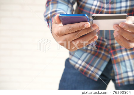 Man hand holding credit card and using smart phone shopping online Man hand holding credit card and using smart phone shopping online 76290504