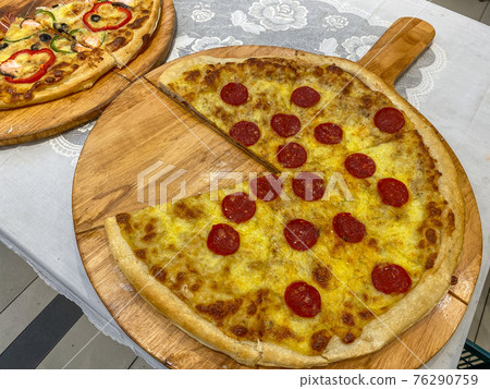 Pepperoni pizza with salami on wooden tray without a slice 76290759