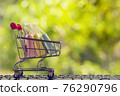 Online shopping, e-commerce concept: Paper shopping bags in a trolley or shopping cart  in the natural green background. purchase of products on internet can purchase goods from foreign countries 76290796