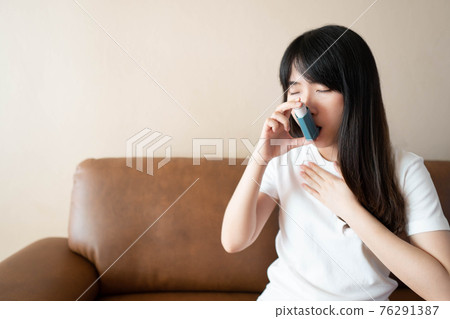 Young asian woman using blue asthma inhaler for relief asthma attack. Pharmaceutical products is used to prevent and treat wheezing and shortness of breath caused asthma or COPD. Health care. Young asian woman using blue asthma inhaler for relief asthma attack. Pharmaceutical products is used to prevent and treat wheezing and shortness of breath caused asthma or COPD. Health care. 76291387