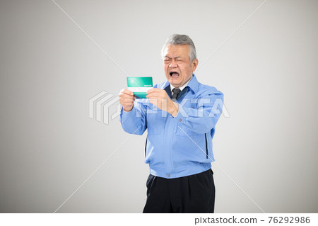 Senior man in work clothes looking at passbook Senior man in work clothes looking at passbook 76292986