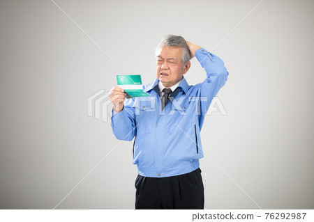 Senior man in work clothes looking at passbook 76292987
