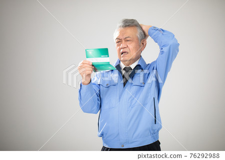 Senior man in work clothes looking at passbook 76292988