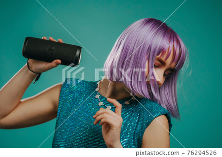 Trendy woman with dyed purple hair listening to music by wireless portable speaker - modern sound Trendy woman with dyed purple hair listening to music by wireless portable speaker - modern sound 76294526