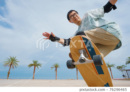 Hello Summer Surfers people Asian having fun with surfboards or surf skate around city streets background on a summer day. Free relax lifestyle and millennial trend concept 76296465