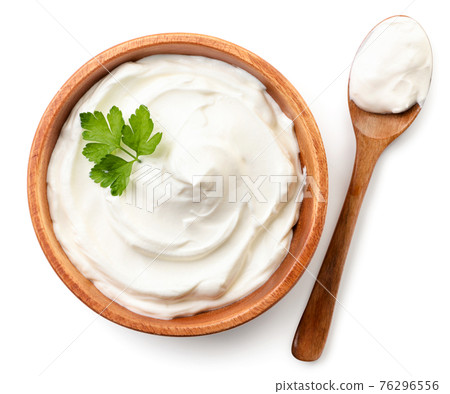 Sour cream in a wooden plate and spoon on a white background, isolated. The view from top Sour cream in a wooden plate and spoon on a white background, isolated. The view from top 76296556