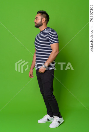 Young bearded Indian man against green background Young bearded Indian man against green background 76297303