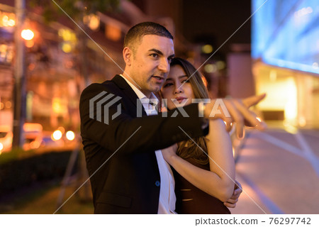 Portrait of couple traveling outdoors at night in the city at Bangkok Thailand Portrait of couple traveling outdoors at night in the city at Bangkok Thailand 76297742