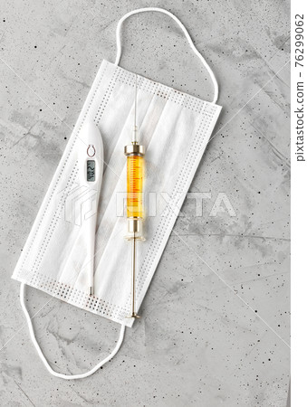 Protective medical mask, glass syringe with vaccine and thermometer, the concept of controlling the incidence of various viruses. Protective medical mask, glass syringe with vaccine and thermometer, the concept of controlling the incidence of various viruses. 76299062
