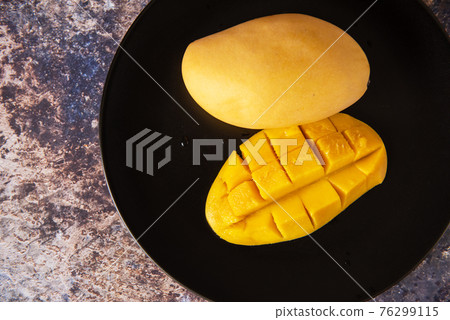 Fresh yellow mango fruit in a black plate Fresh yellow mango fruit in a black plate 76299115