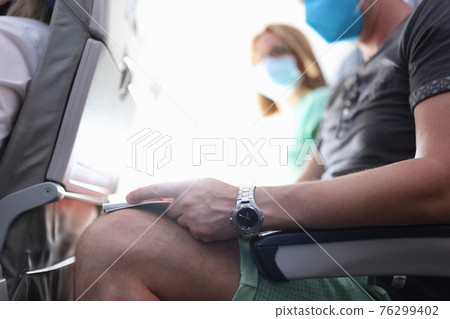 People in medical protective masks are sitting in aircraft cabin 76299402