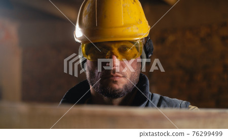 Male carpenter adjusting hardhat during work Male carpenter adjusting hardhat during work 76299499